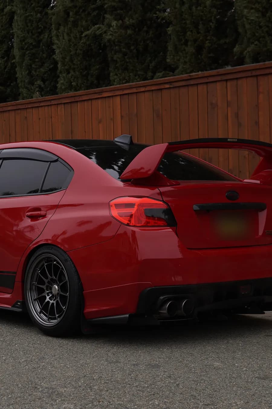 Red 2015 Subaru WRX with STI wing, rear three-quarter view